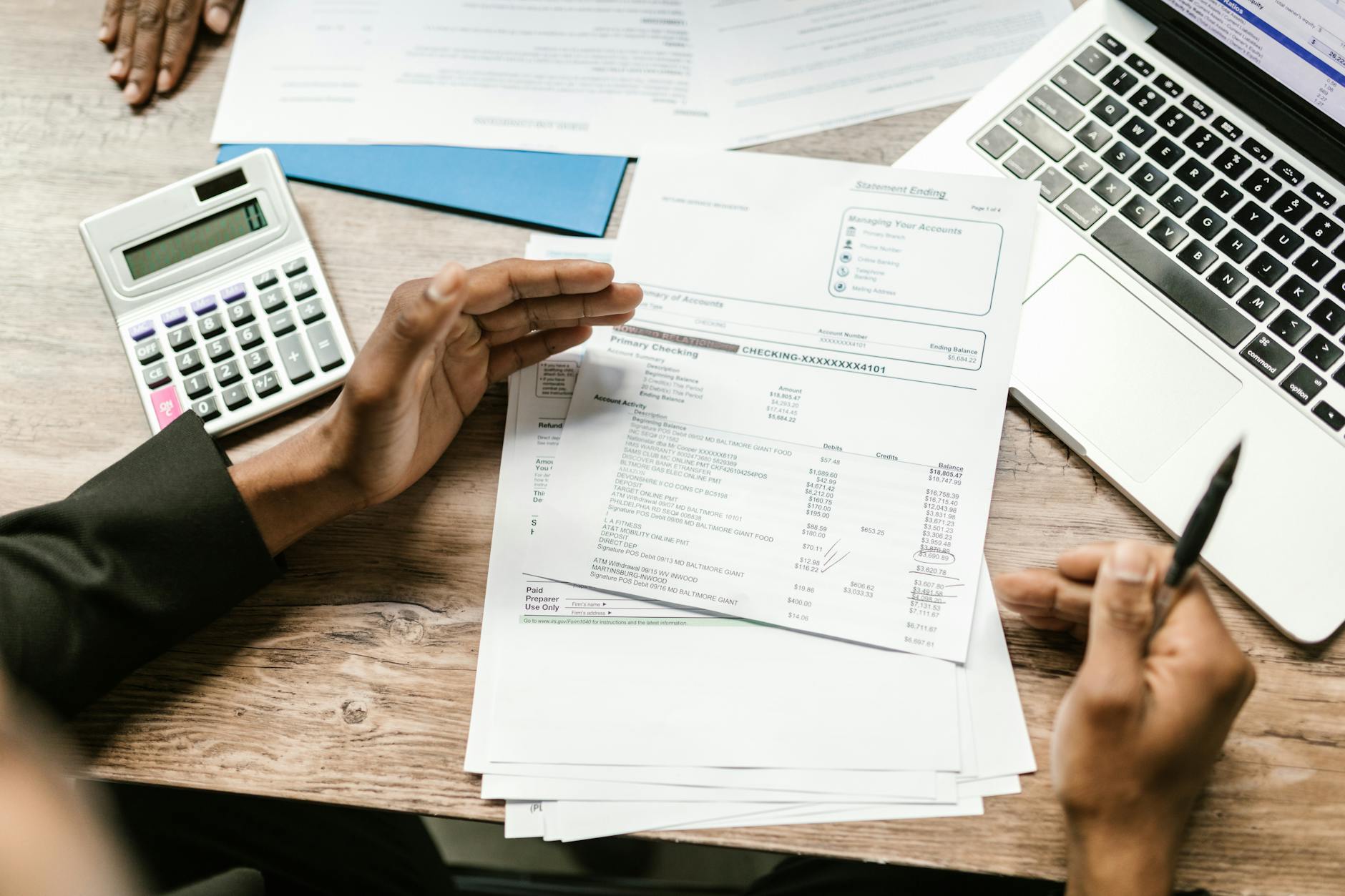 Hands holding financial documents with calculator and laptop for business cost analysis
