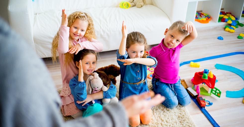 Children in childcare centre with hands raised