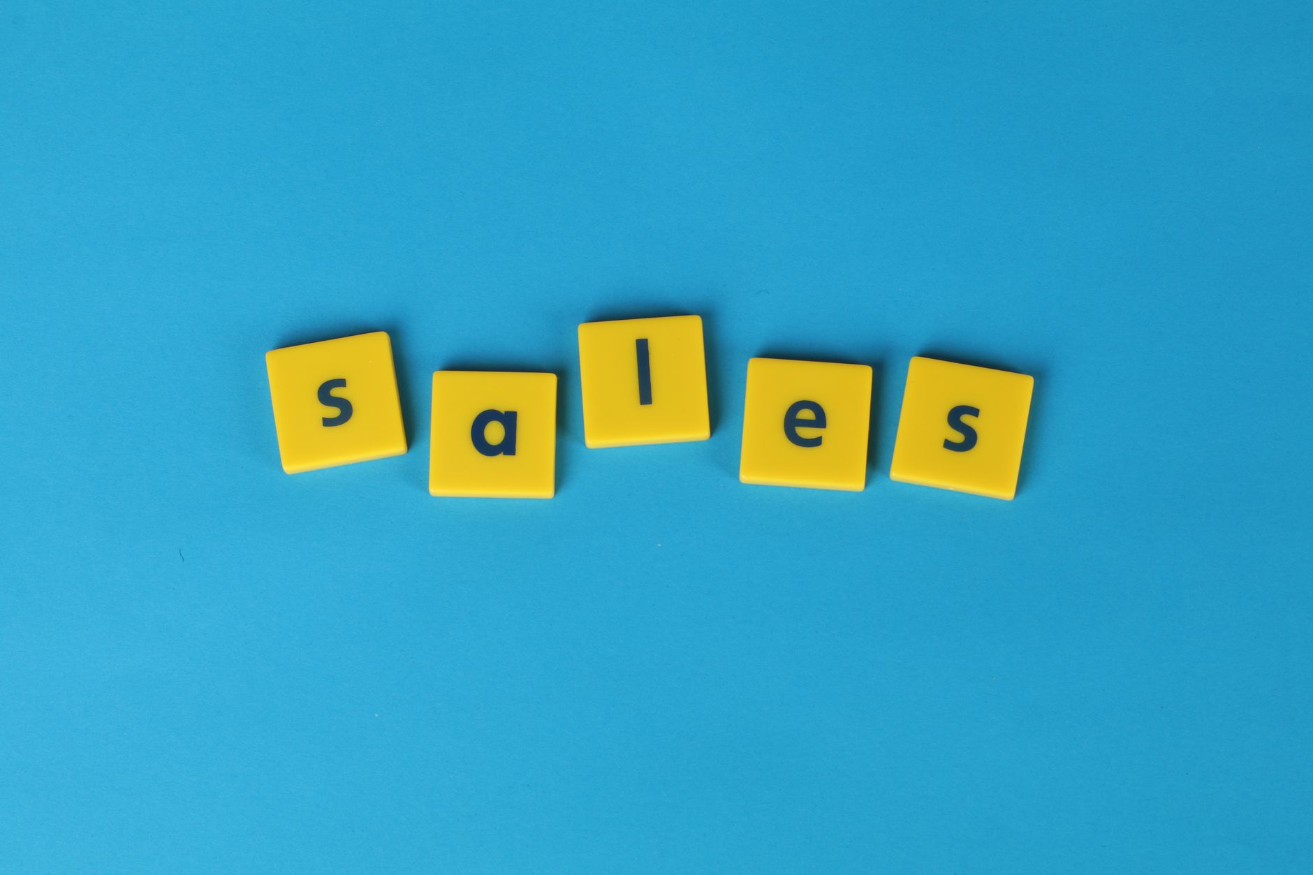 Yellow Scrabble tiles spelling 'sales' on a vibrant blue background. Perfect for marketing and business themes.